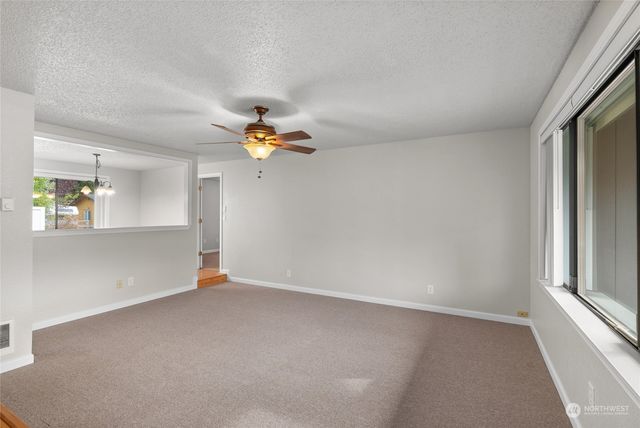 an empty room with windows and chandelier fan
