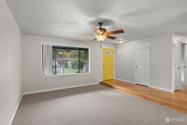 an empty room with windows and fan