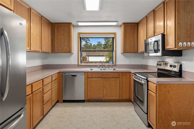 a kitchen with stainless steel appliances granite countertop a stove a sink and a microwave