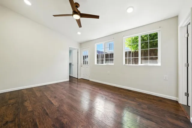 a view of an empty room with wooden floor and a window