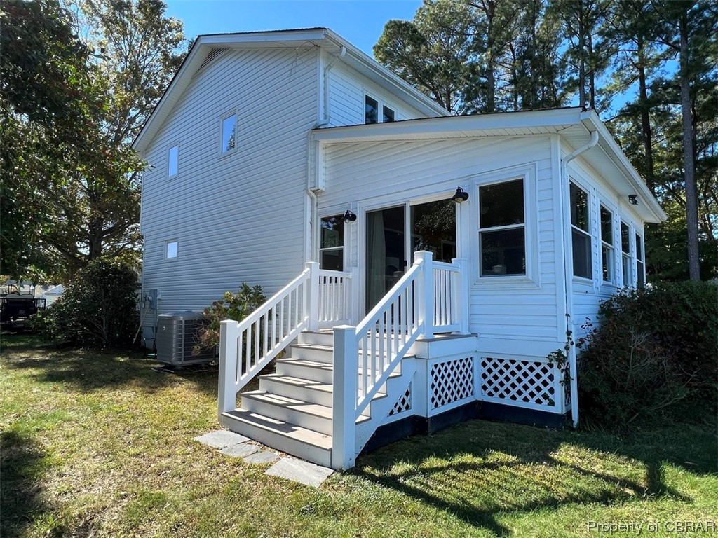 View of front of property featuring a front lawn and central AC