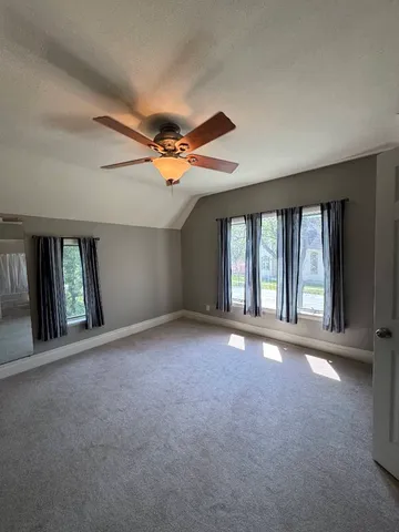 a view of an empty room with a window and a ceiling fan