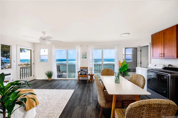 a living room with furniture dining table a large window wooden floor and a rug
