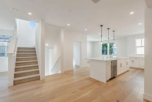 a large white kitchen with a refrigerator a stove a sink and a large window