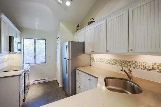 a kitchen with stainless steel appliances granite countertop a sink and a refrigerator