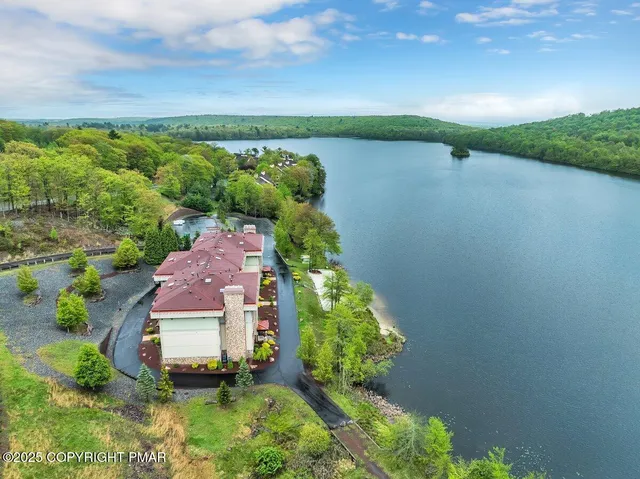 an aerial view of a house with garden space and a lake view in back