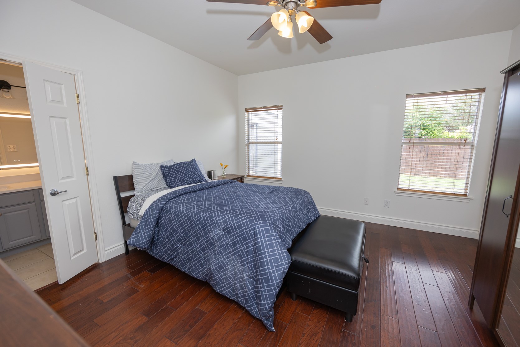 11500 Dimmit Street Manor, TX 78653 - Photo 8 of 14 Spacious room featuring wood-finish flooring, white walls, two windows with blinds, and a ceiling fan with integrated lighting