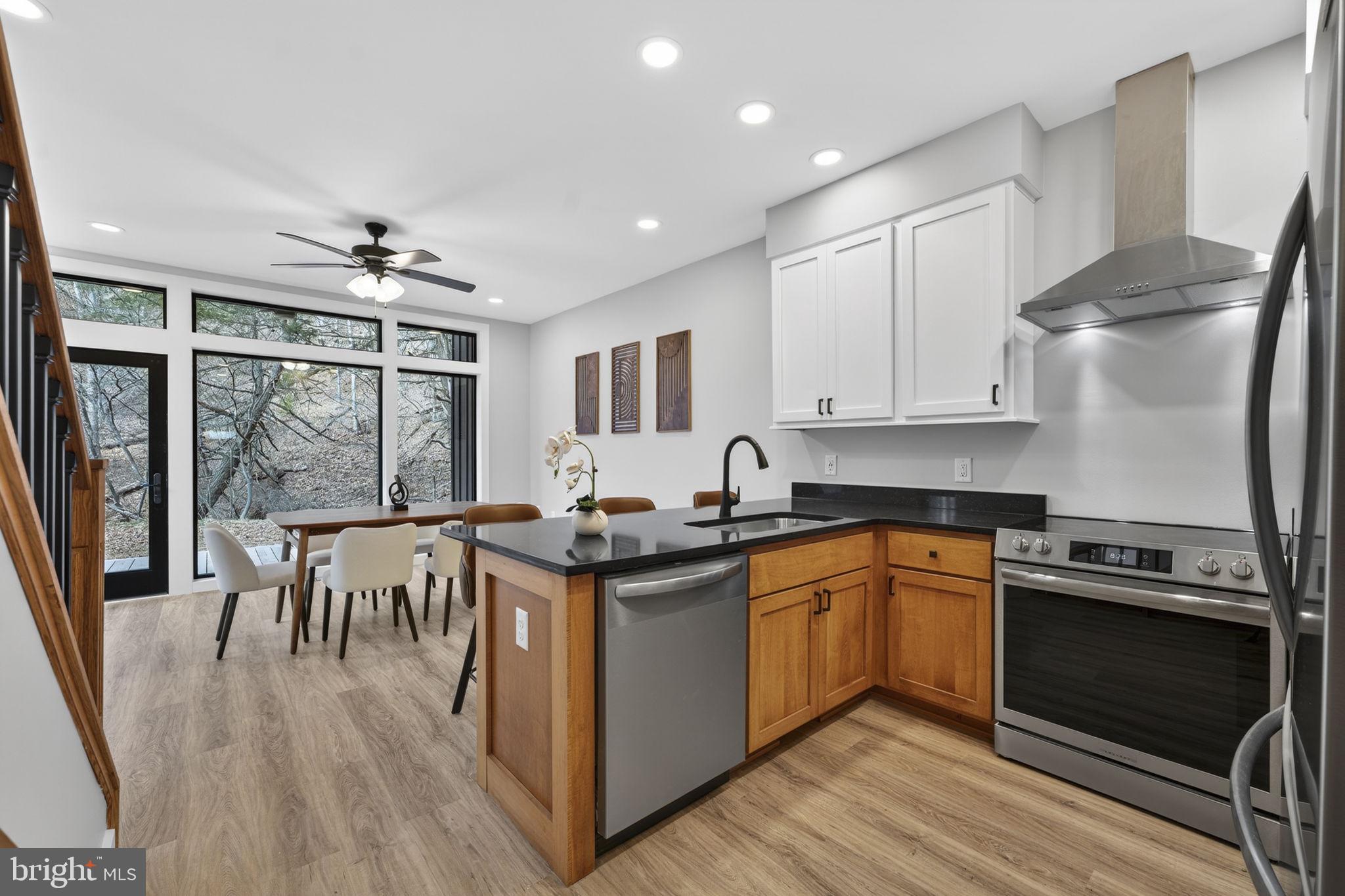 1956 Dove Hollow Road Mathias, WV 26812 - Photo 35 of 113 a kitchen with stainless steel appliances granite countertop a stove top oven a sink a dining table and chairs with wooden floor