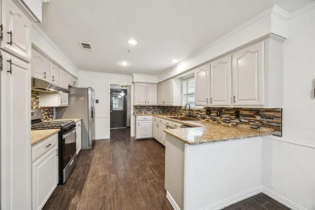 a kitchen with stainless steel appliances granite countertop a stove top oven a sink and a refrigerator