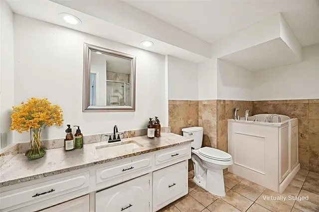 a bathroom with a granite countertop toilet sink and mirror