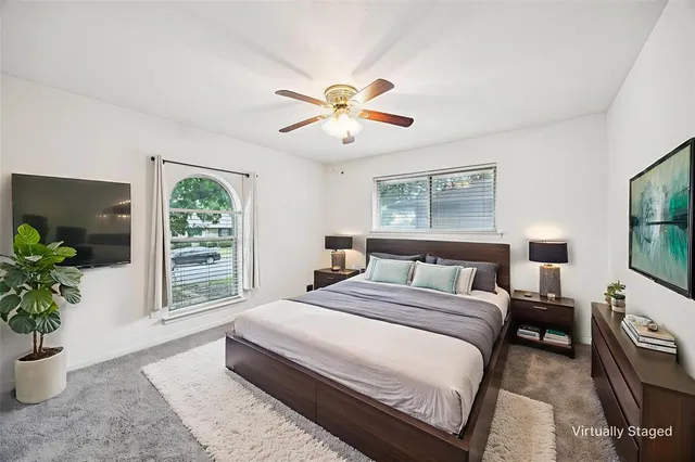 a spacious bedroom with a large bed a chandelier and windows