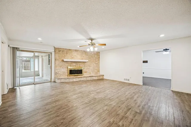 a view of an empty room with wooden floor and a fireplace