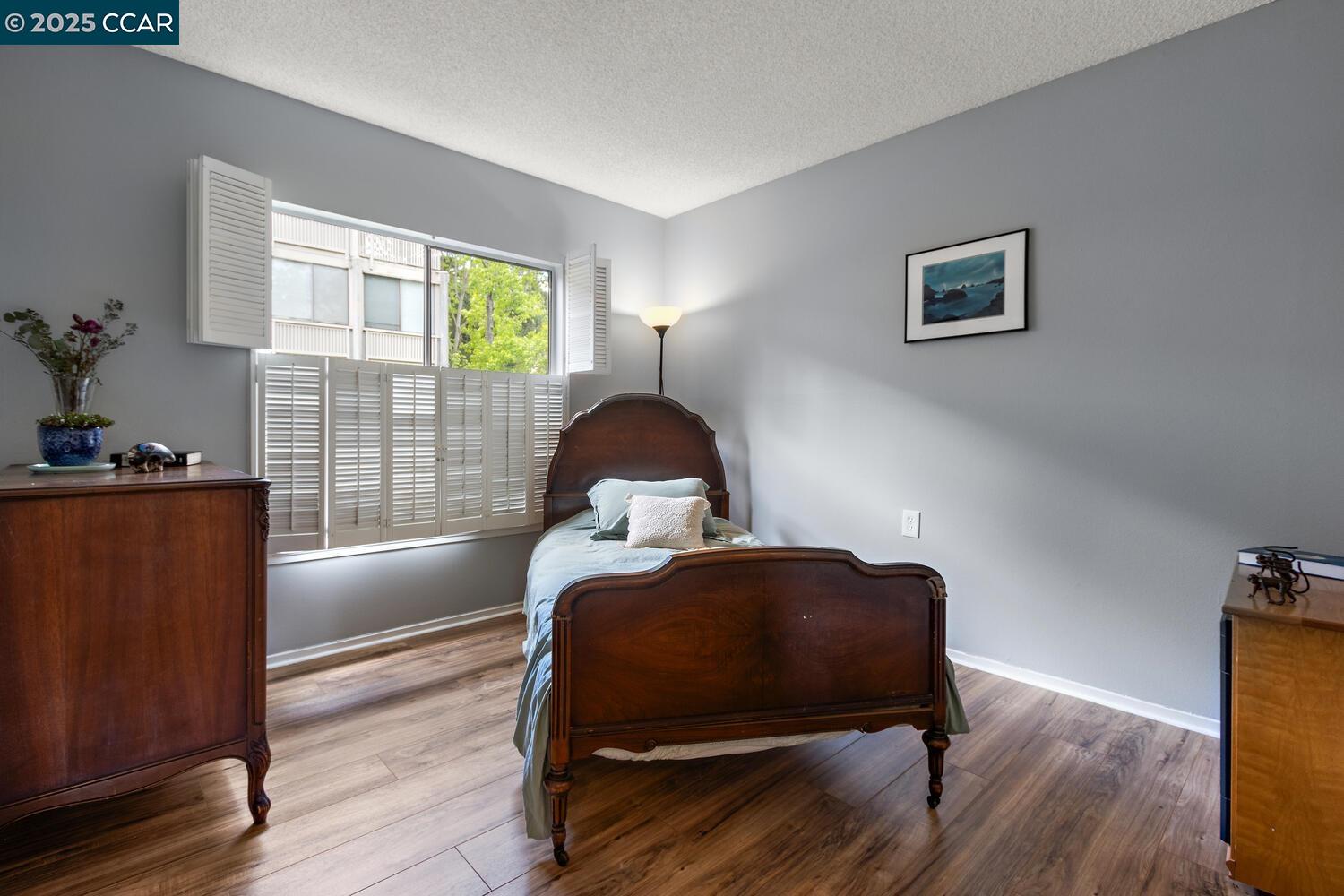 1244 Singingwood Court, Unit 1 Walnut Creek, CA 94595 - Photo 23 of 46 a bedroom with a bed and wooden floor