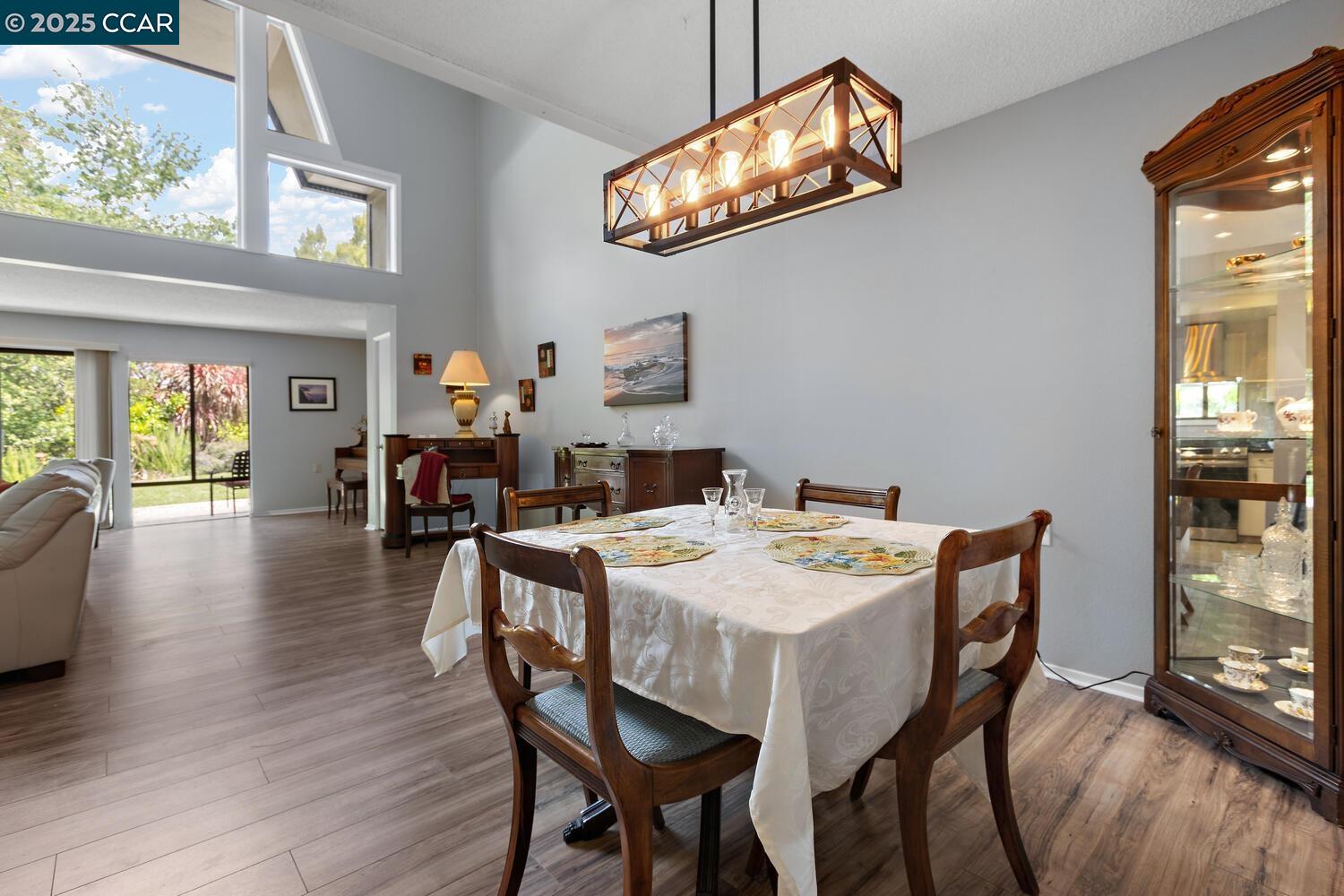 1244 Singingwood Court, Unit 1 Walnut Creek, CA 94595 - Photo 3 of 46 a dining room with wooden floor a chandelier a wooden table and chairs