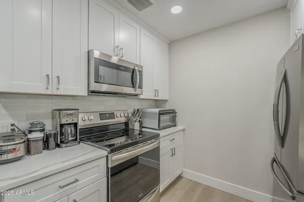 a kitchen with a sink dishwasher a stove and white cabinets with wooden floor