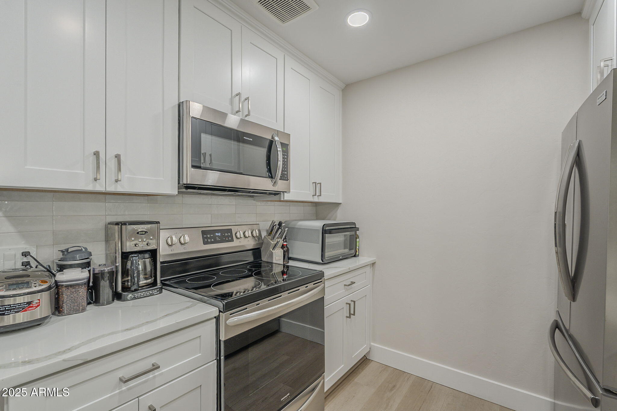 2038 East River Road, Unit 101 Tucson, AZ 85718 - Photo 5 of 21 a kitchen with stainless steel appliances white cabinets and a stove top oven