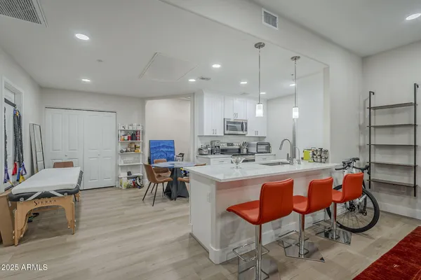 a kitchen with stainless steel appliances granite countertop a table chairs stove and sink