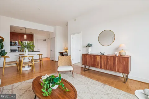 a living room with furniture a mirror and wooden floor