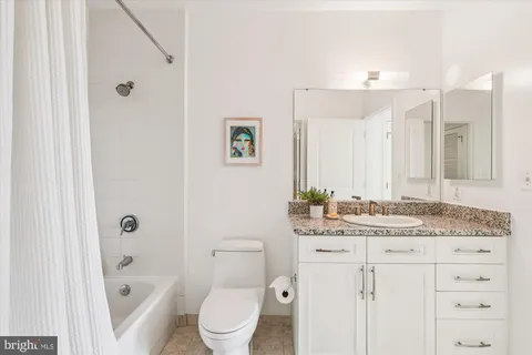 a bathroom with a granite countertop sink a toilet mirror and shower