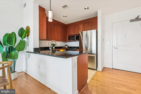 a kitchen with stainless steel appliances granite countertop a refrigerator a stove a sink and a potted plant