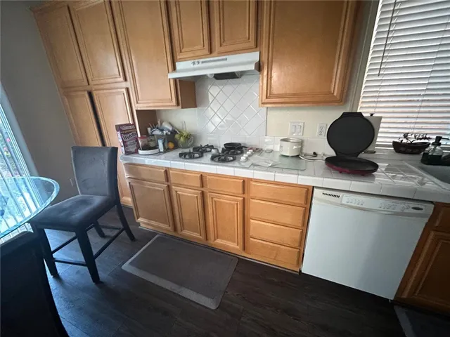 a kitchen with stainless steel appliances granite countertop a stove a sink dishwasher and cabinets with wooden floor