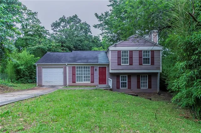 a brick house with a small yard plants and large trees