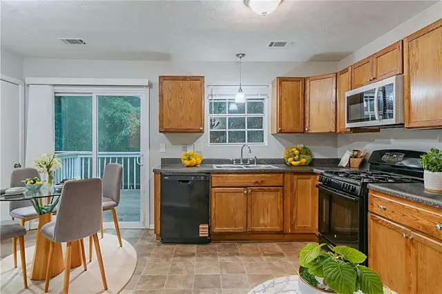 a kitchen with stainless steel appliances granite countertop a stove top oven a sink dishwasher a dining table and chairs with wooden floor