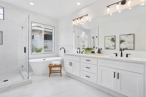 a spacious bathroom with double vanity a mirror a bathtub and shower