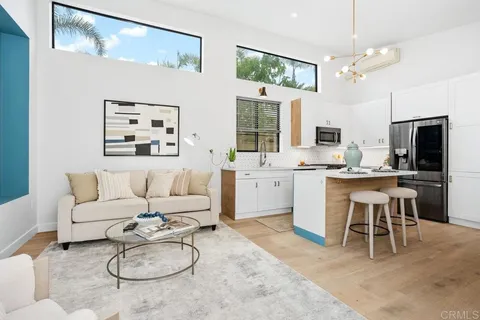 a living room with furniture a flat screen tv and kitchen view