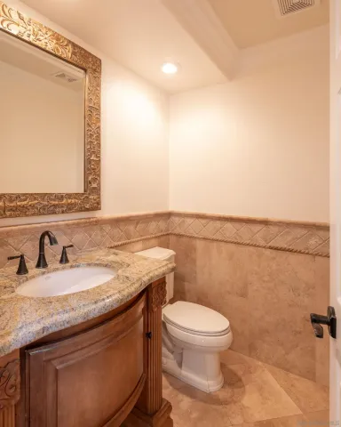 a bathroom with a granite countertop toilet sink and mirror
