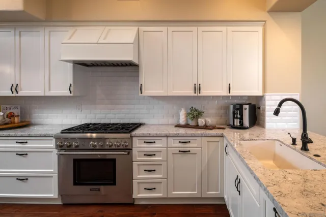 a kitchen with granite countertop white cabinets and appliances