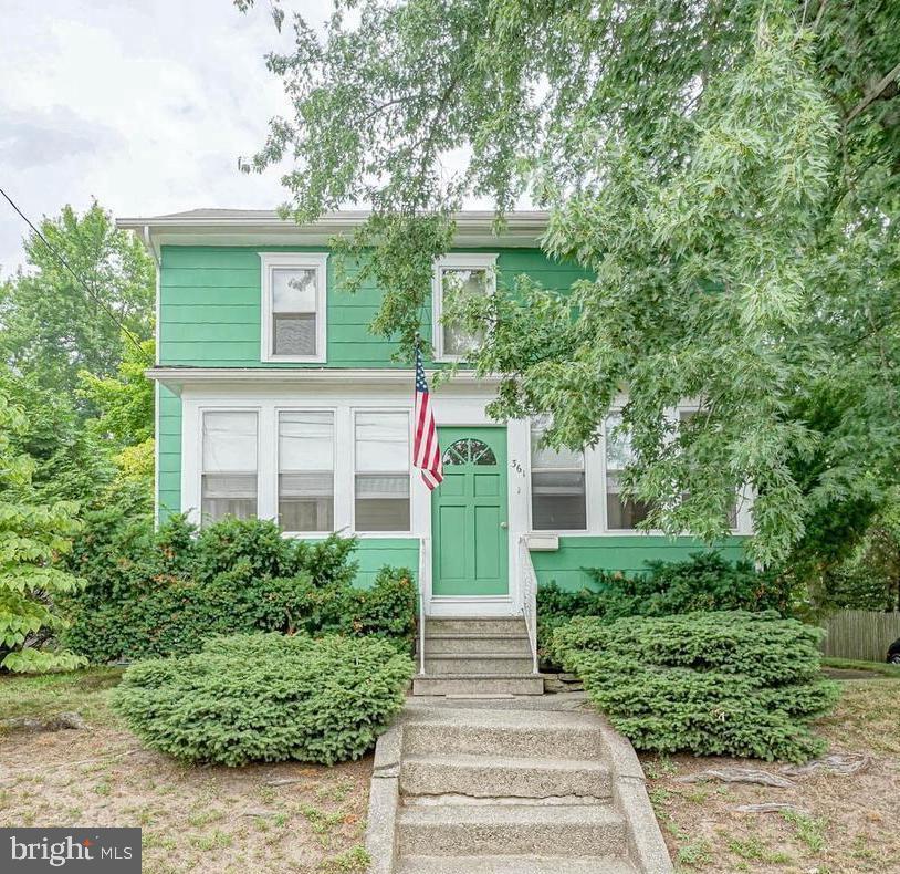 Charming green home with welcoming steps.