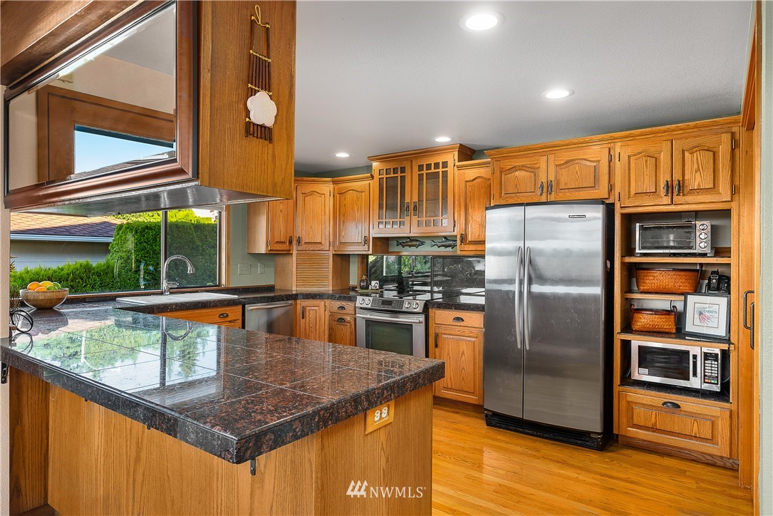 4910 23rd Avenue West Everett, WA 98203 - Photo 12 of 40 a kitchen with stainless steel appliances granite countertop a refrigerator a oven and a sink with wooden floor