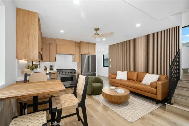 a kitchen with stainless steel appliances kitchen island granite countertop a dining table chairs refrigerator and sink