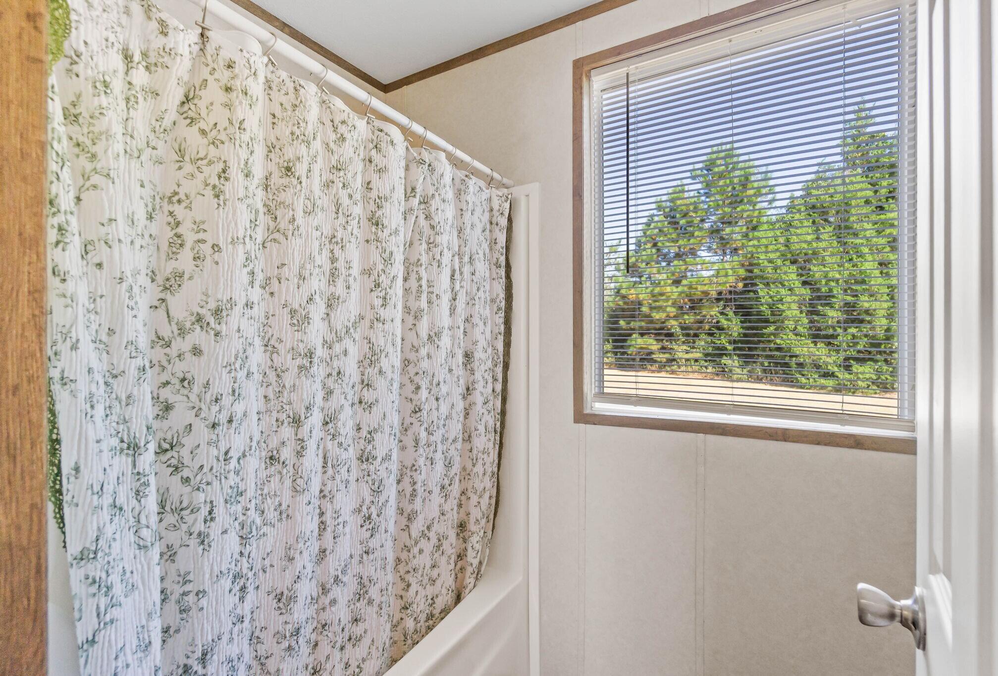 3139 Creek Road Bonifay, FL 32425 - Photo 16 of 41 a bathroom with a shower curtain and a window with blinds