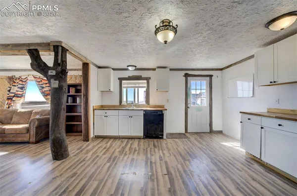a open kitchen with a refrigerator and a wooden floor