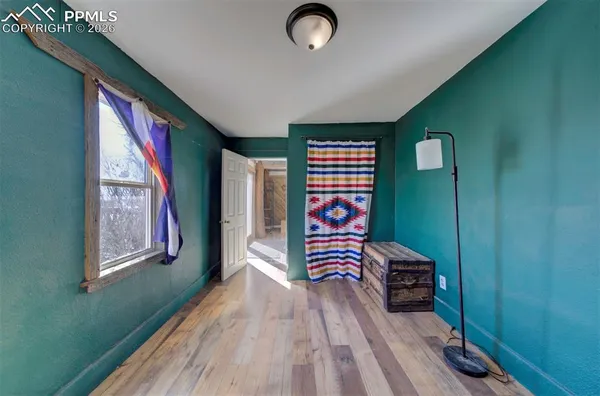a view of an empty room with window and hardwood floor