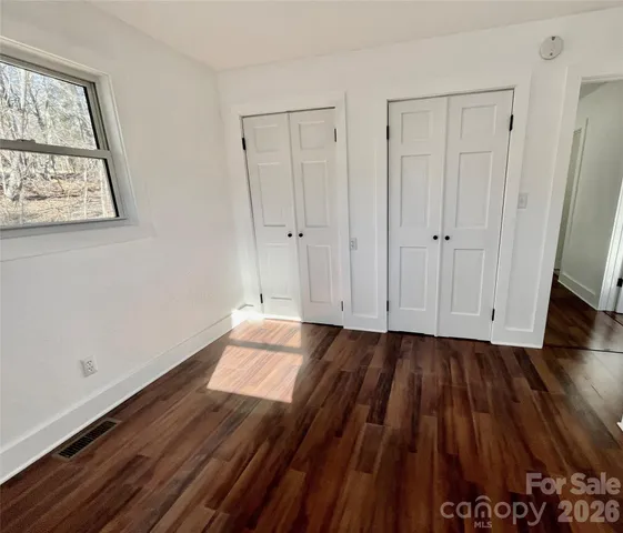 a view of an empty room with wooden floor and closet