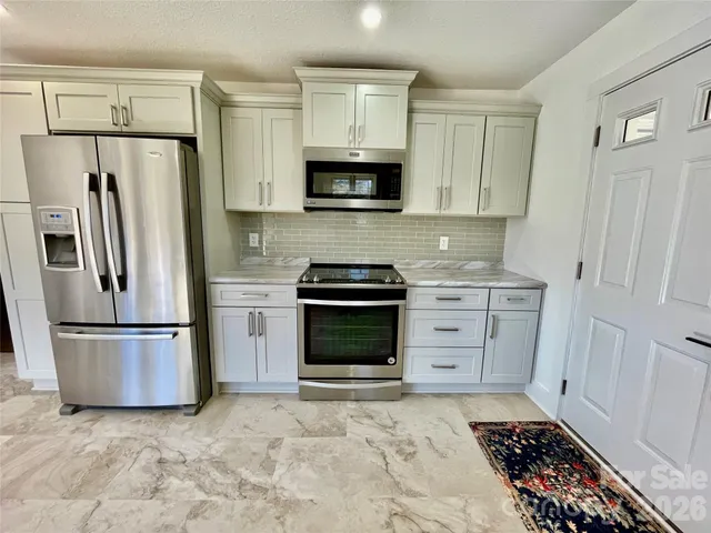 a kitchen with white cabinets and stainless steel appliances