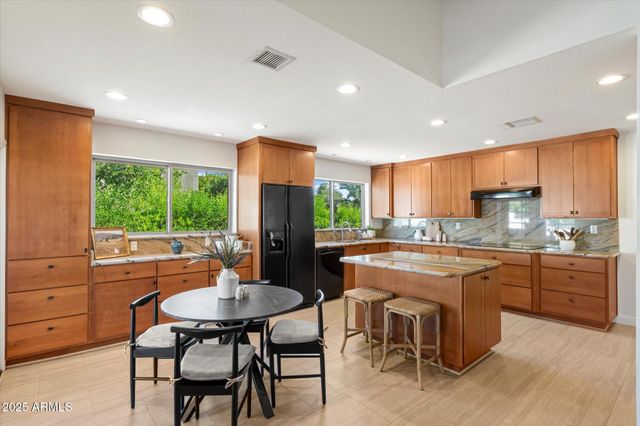 a kitchen with kitchen island granite countertop a table chairs sink and cabinets