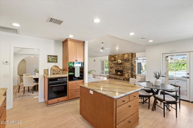 a view of a kitchen with kitchen island a stove a refrigerator a dining table and chairs with wooden floor