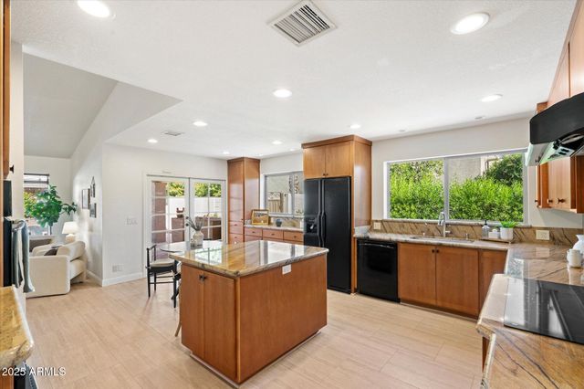 a living room with stainless steel appliances kitchen island granite countertop a refrigerator a sink dishwasher and a stove with wooden floor