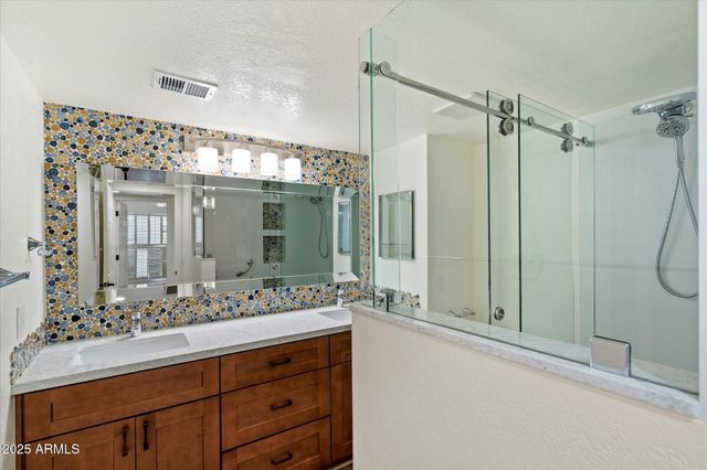 a bathroom with a double vanity sink mirror and shower
