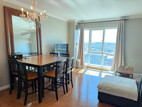 a dining room with wooden floor a chandelier a wooden table and chairs