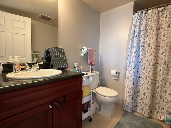 a bathroom with a granite countertop sink toilet and a mirror