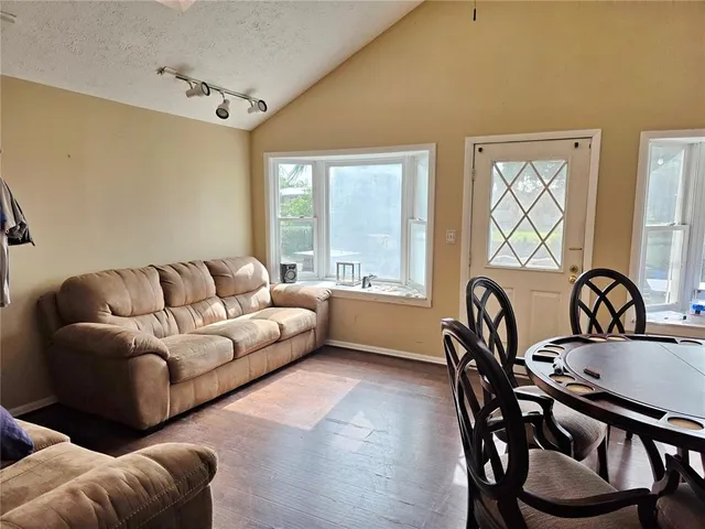 a living room with furniture two window and a wooden floor
