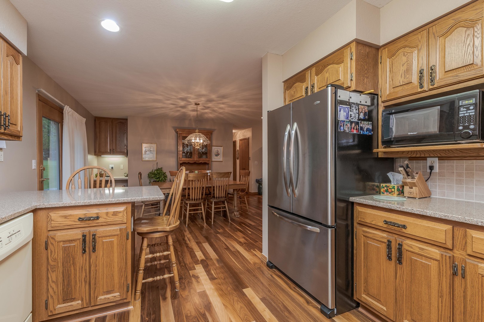 103 East 9th Street Gridley, IL 61744 - Photo 16 of 45 a kitchen with stainless steel appliances granite countertop a refrigerator a stove a sink a dining table and chairs with wooden floor