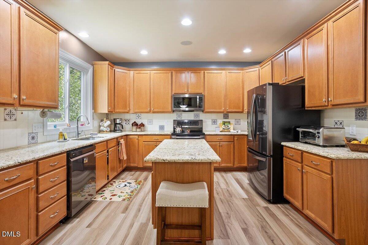 9208 Palm Bay Circle Raleigh, NC 27617 - Photo 22 of 54 a kitchen with wooden floors wooden cabinets and stainless steel appliances