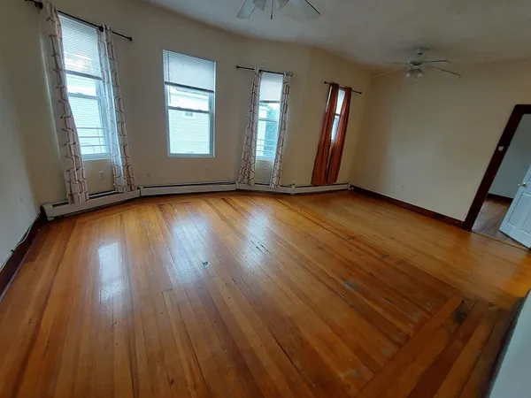 an empty room with wooden floor and windows