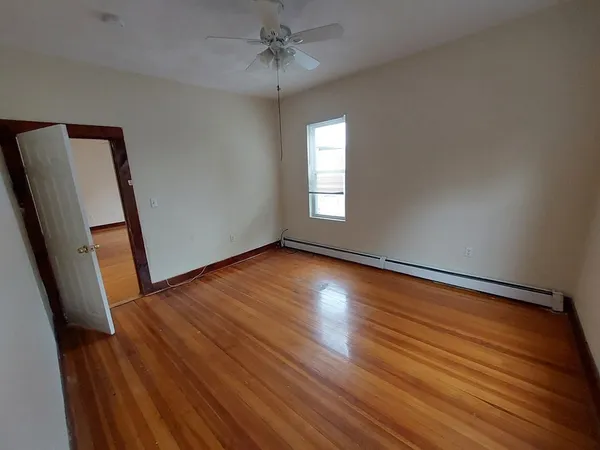 a view of empty room with wooden floor and fan